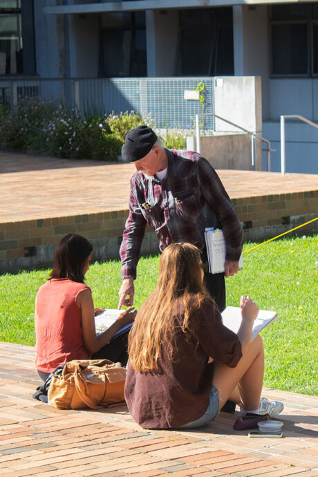 teacher chatting with students in courtyard